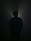 A silhouette stands illuminated in the darkness