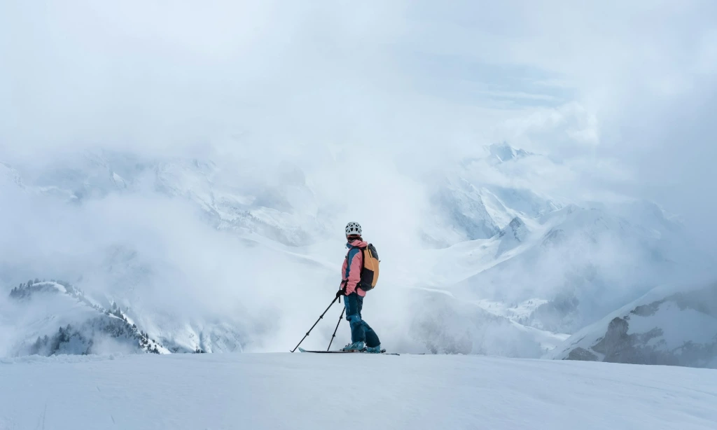 man in orange jacket and black pants standing on snow covered ground ski montagne crux nutrition